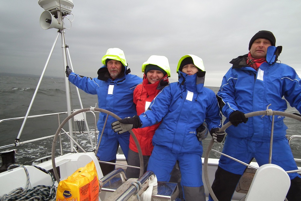 Grupa żeglarzy na łodzi w niebieskich sztormiakach Hornet